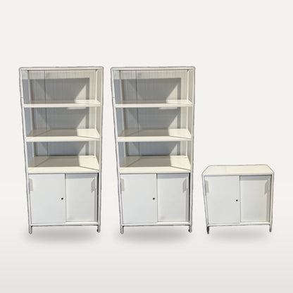 Två höga vita metallskåp tillsammans med matchande låg modul